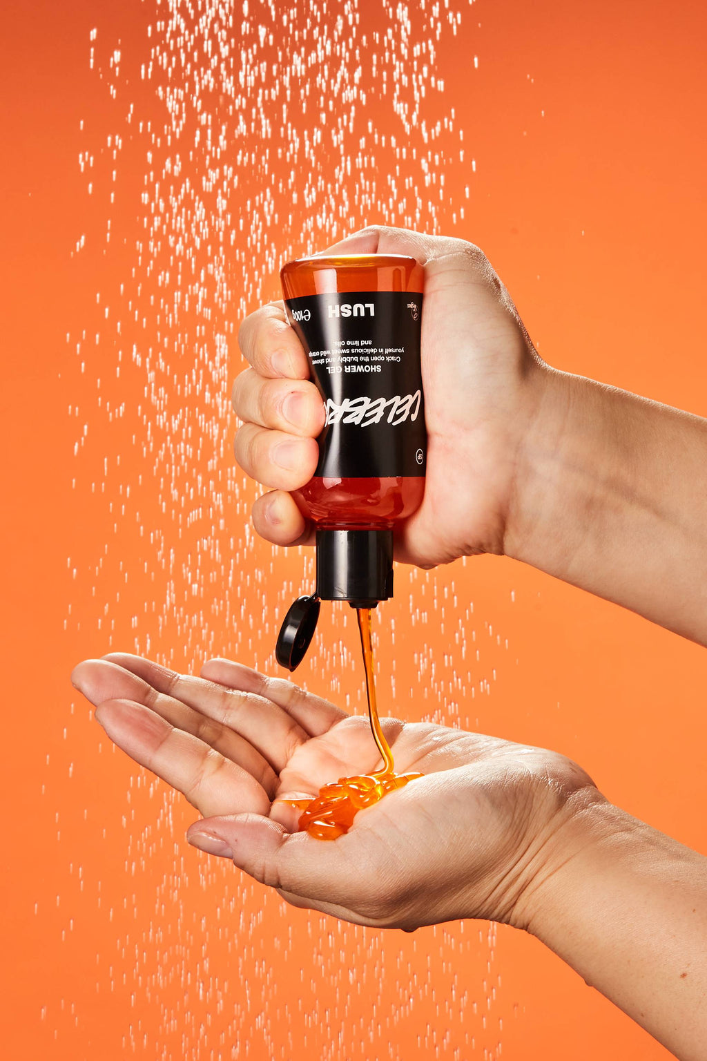 A close-up of the model's hand as they squeeze the Celebrate shower gel into their hand under running shower water.
