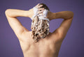 Someone massages vibrant purple Daddy-O shampoo into the back of their head, creating a mass of lilac coloured bubbles.